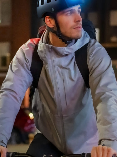 Urban commuter wearing black FEND Super folding bicycle helmet with ultra-bright lights, cycling in New York City at night.